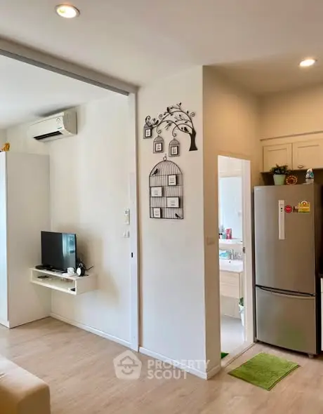 Modern living room with TV, air conditioning, and kitchen view in open layout apartment.