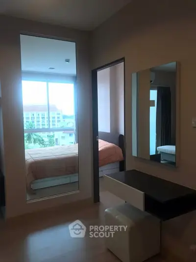 Modern bedroom with large mirror and natural light, featuring a stylish vanity area.