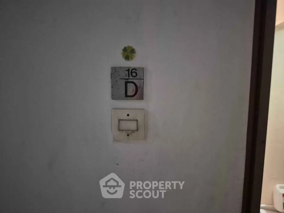 Apartment door with unit number 16D and light switch, simple and minimalistic design.