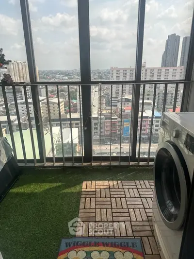 High-rise balcony with artificial grass and washing machine offering panoramic city views.