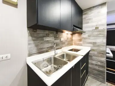 Modern kitchen with sleek cabinetry and dual sink in compact layout