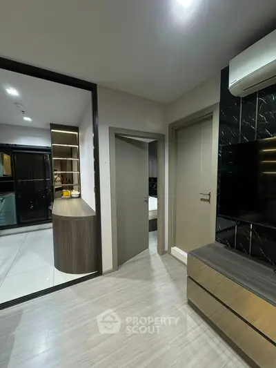 Modern apartment interior with sleek design and stylish furniture, featuring a TV and air conditioning unit.
