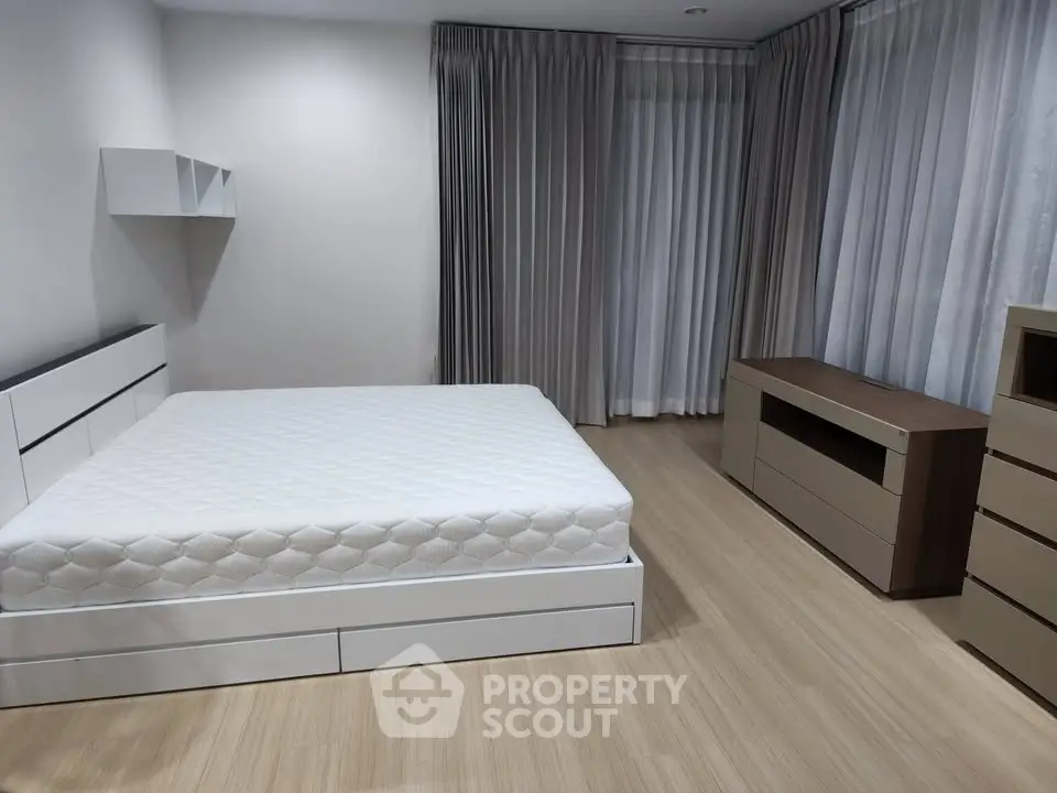 Spacious bedroom with modern furniture and large windows for natural light.