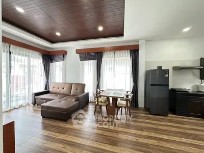 Spacious open-plan living room with modern kitchen and elegant dining area, featuring large windows and stylish decor.