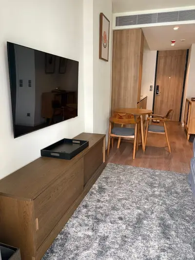 Modern living room with wall-mounted TV and stylish wooden furniture in a cozy apartment.