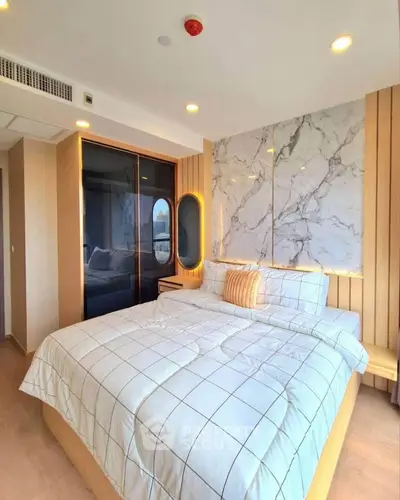 Luxurious bedroom with modern design and marble accents, featuring a cozy bed and ambient lighting.