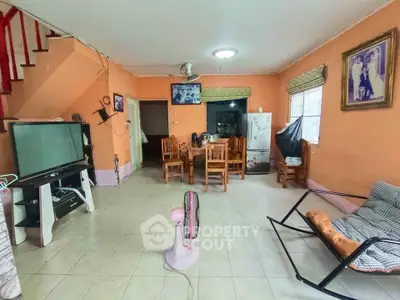 Spacious living room with dining area, featuring a TV, fan, and cozy seating, perfect for family gatherings.