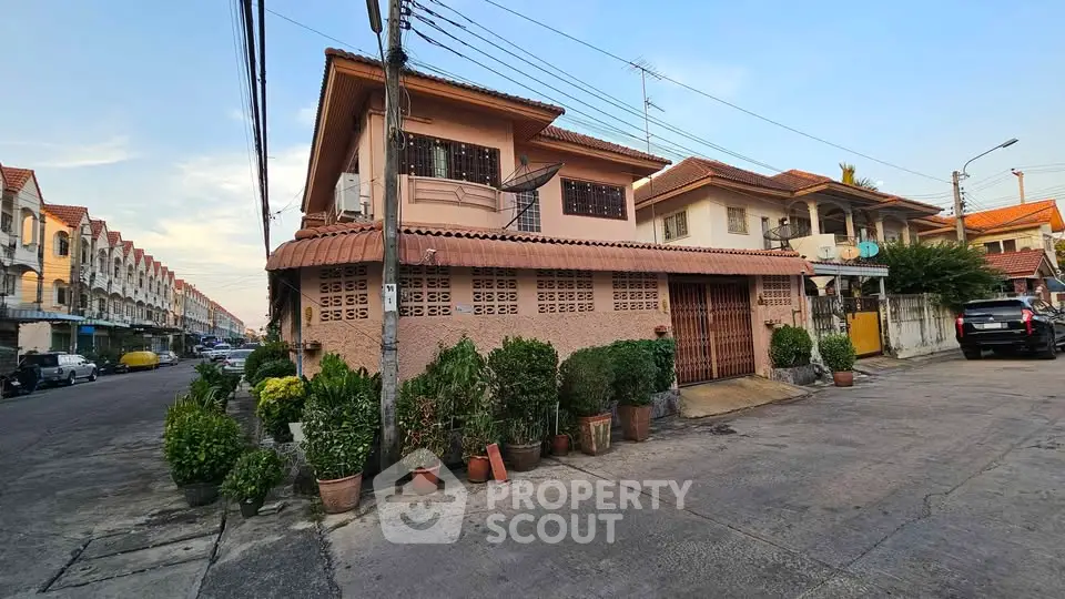 Charming two-story house with lush potted plants in a serene suburban neighborhood.