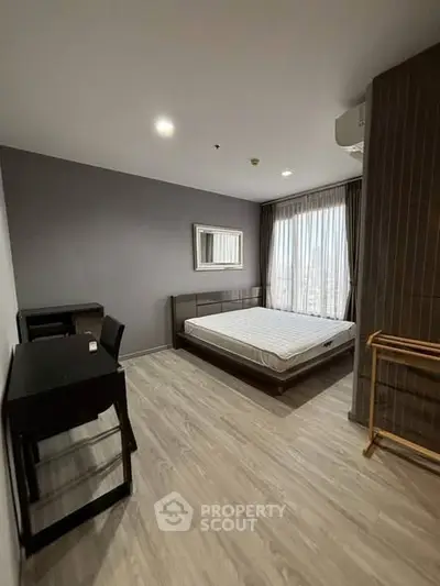 Modern bedroom with large window and stylish furnishings in a contemporary apartment.