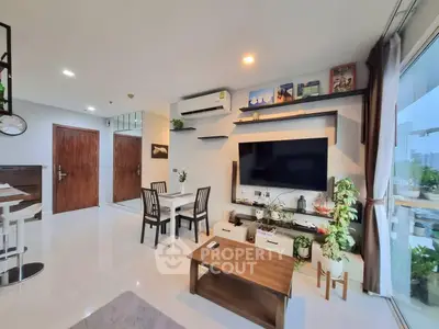 Spacious modern living room with large TV, stylish decor, and city view.