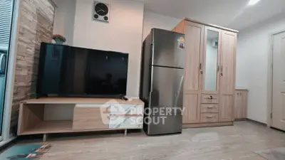 Modern living room with sleek TV, stylish wooden cabinet, and stainless steel fridge