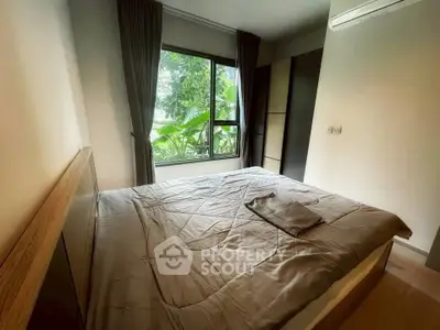 Cozy bedroom with large window and lush greenery view, featuring modern decor and air conditioning.