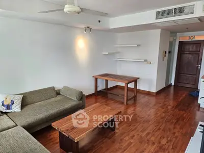 Spacious living room with wooden flooring and modern furniture in a cozy apartment.