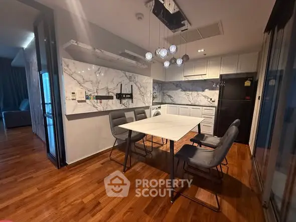 Modern dining area with marble accents and wooden flooring in a stylish apartment.