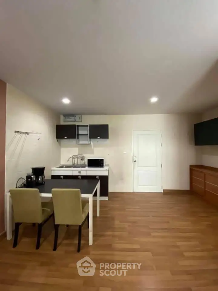 Modern kitchen with dining area, featuring sleek cabinetry and hardwood flooring.