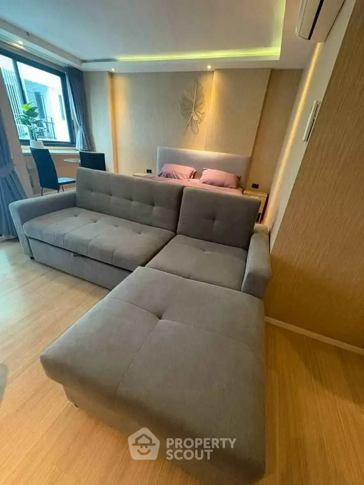Modern living room with stylish sofa and cozy bedroom area, perfect for urban living.