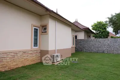 Charming suburban home with lush green lawn and stone wall, perfect for family living.