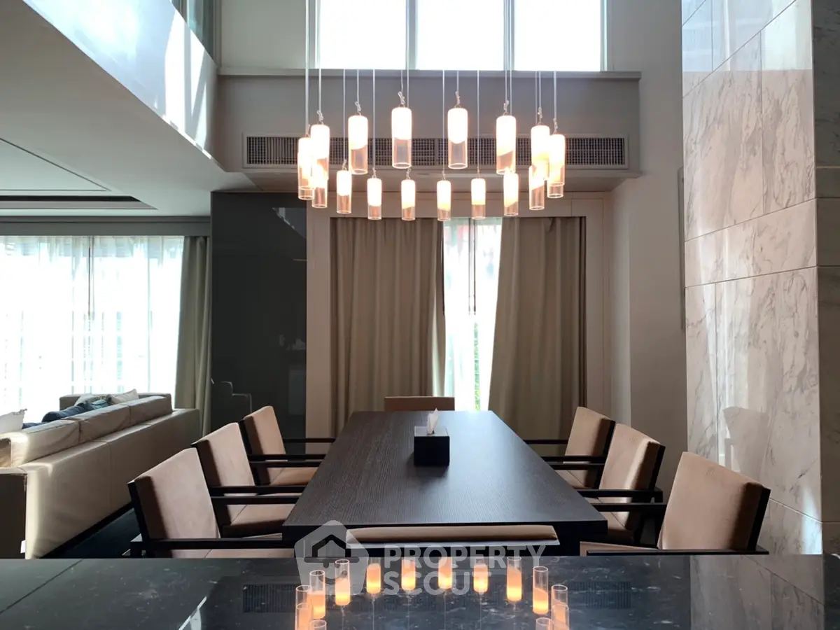 Luxurious dining area with elegant chandelier and modern decor in a spacious living room setting.