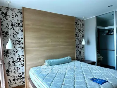 Spacious bedroom with elegant floral wallpaper and modern lighting fixtures.