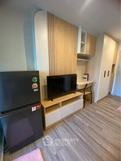Modern living room with sleek TV unit and compact fridge, perfect for urban living.