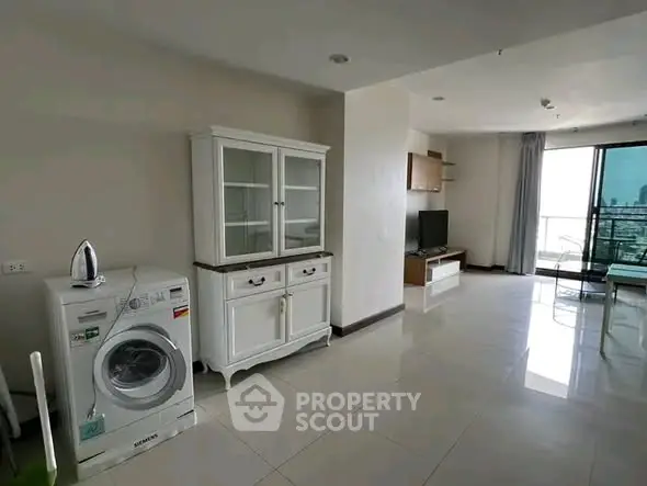 Spacious living area with modern appliances and balcony view in a stylish apartment.