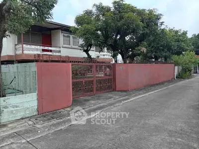 Charming suburban house with red gate and lush greenery