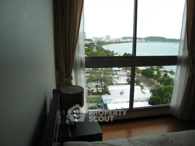 Stunning bedroom view with floor-to-ceiling window overlooking scenic waterfront and lush greenery.