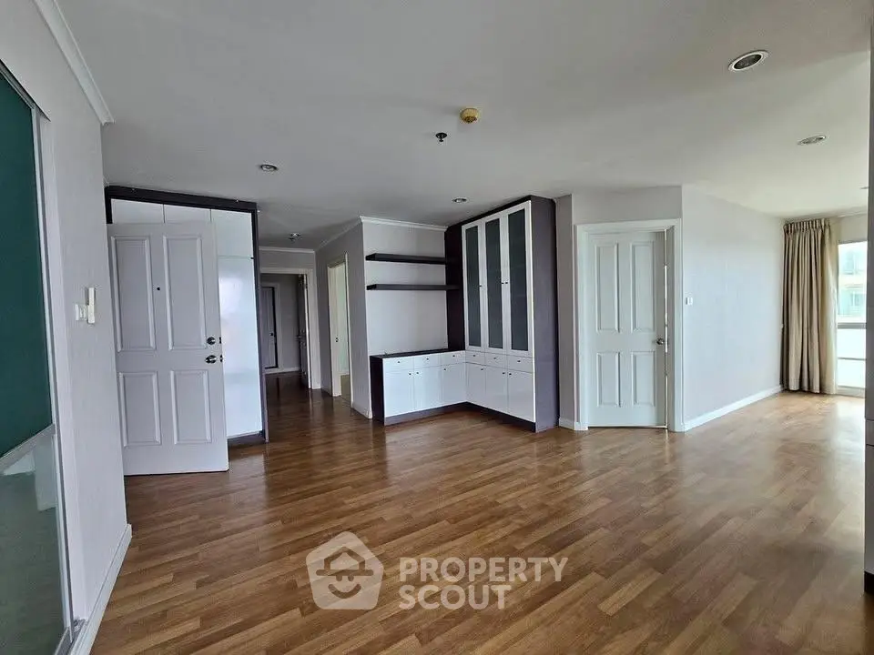 Spacious apartment interior with wooden flooring and built-in storage cabinets.