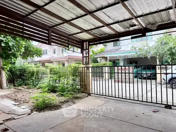 Spacious covered parking area with metal gate in a residential neighborhood.