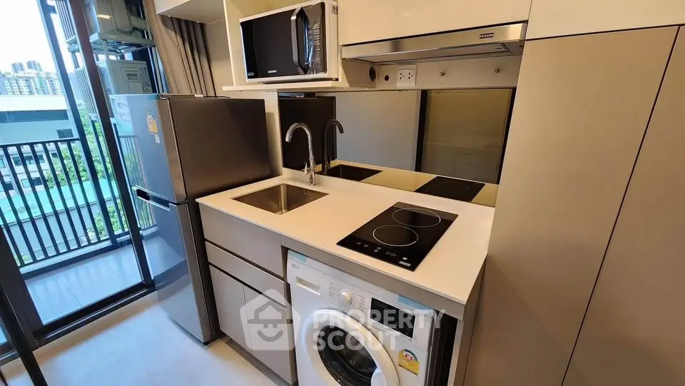Modern compact kitchen with appliances and balcony view in urban apartment