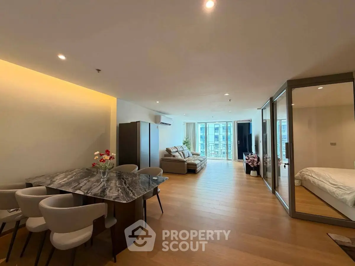 Spacious modern living room with open layout and elegant dining area, featuring large windows and stylish decor.