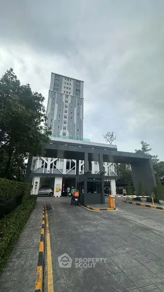 Modern high-rise building with sleek entrance and lush greenery, perfect for urban living.