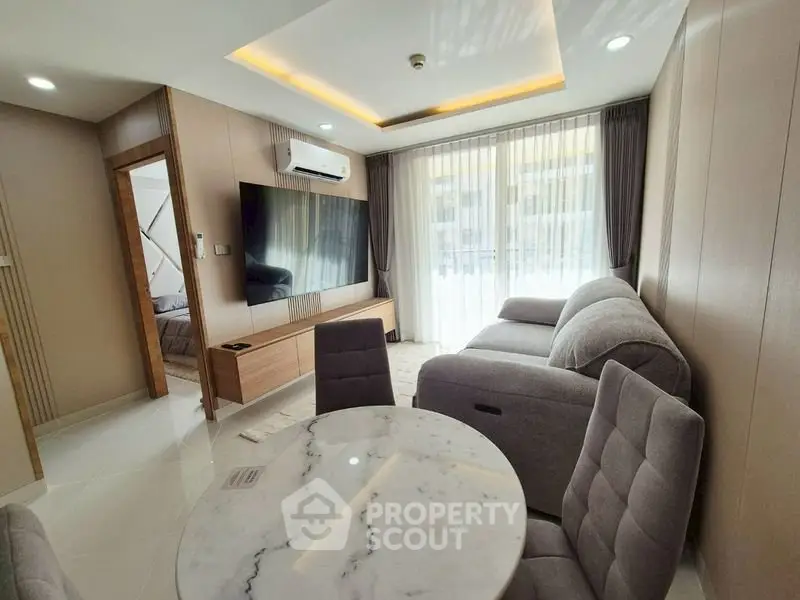 Modern living room with stylish furniture and large TV, featuring elegant lighting and natural light from large windows.