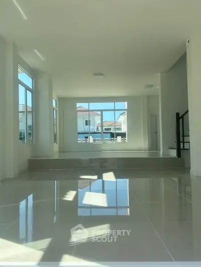 Spacious modern living room with large windows and glossy tiled floors, offering abundant natural light and a serene ambiance.