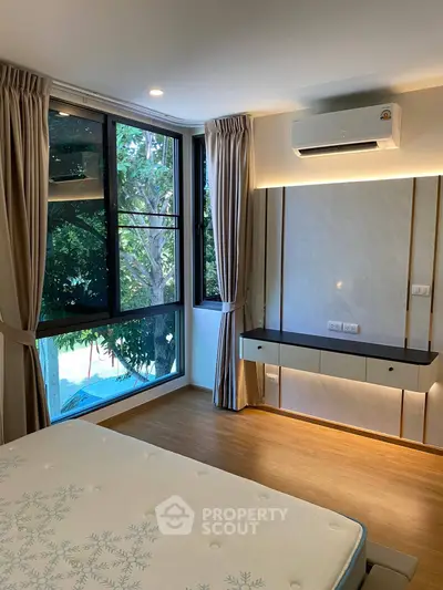 Modern bedroom with large windows and air conditioning, featuring elegant curtains and wooden flooring.
