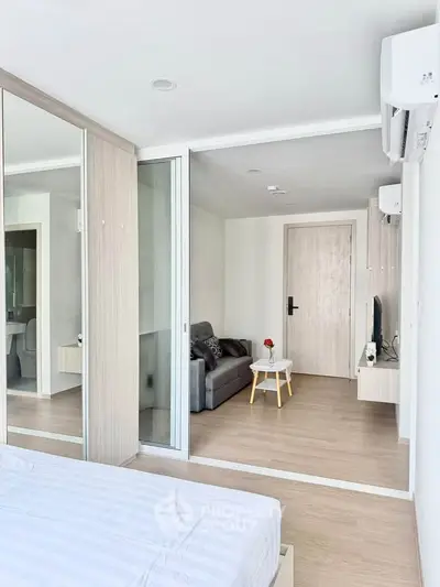 Modern bedroom with sliding glass doors and cozy living area, featuring sleek design and natural light.