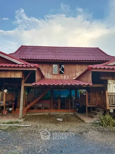 Charming traditional wooden house with red tiled roof and spacious porch, perfect for serene living.