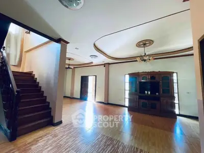Spacious living room with elegant wooden staircase and stylish ceiling design.
