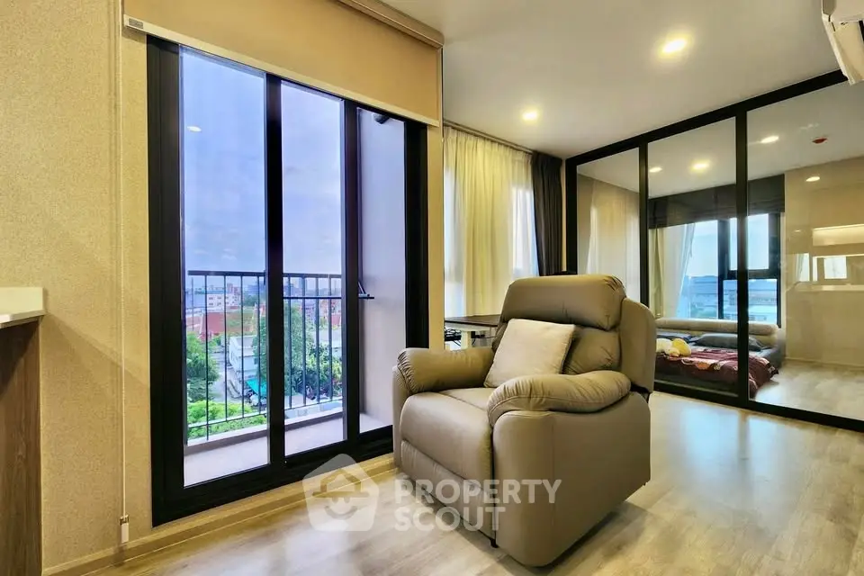 Modern living room with large windows and cozy armchair, offering a bright and inviting atmosphere.