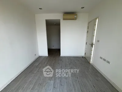 Spacious empty room with wooden flooring and air conditioning unit