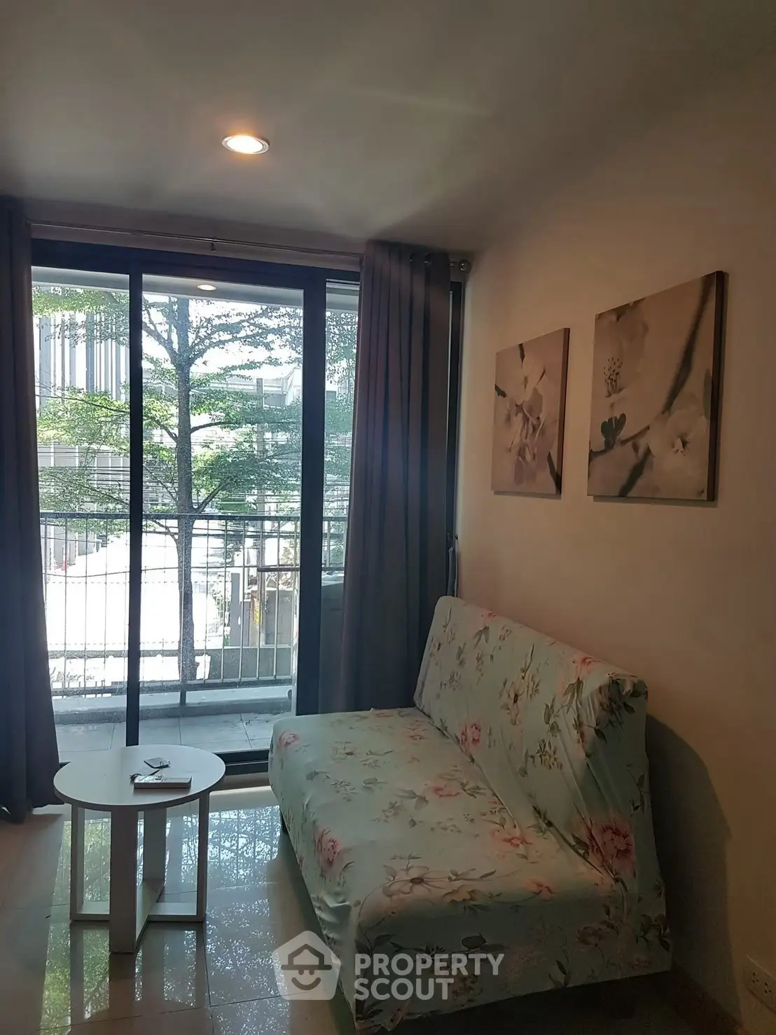 Cozy living room with floral sofa and balcony view, perfect for relaxation.