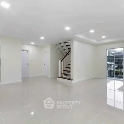 Spacious modern living room with staircase and large windows for natural light.