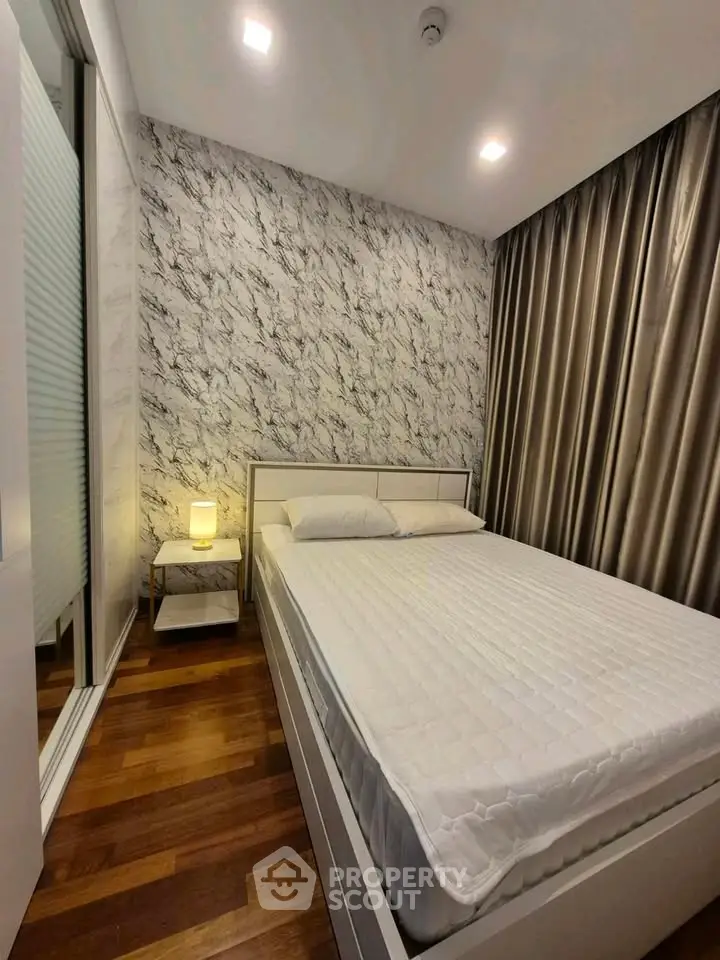 Modern bedroom with stylish decor and wooden flooring, featuring a comfortable bed and elegant lighting.