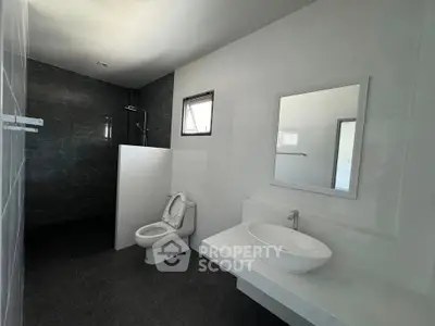 Modern minimalist bathroom with sleek fixtures and dark tile accents