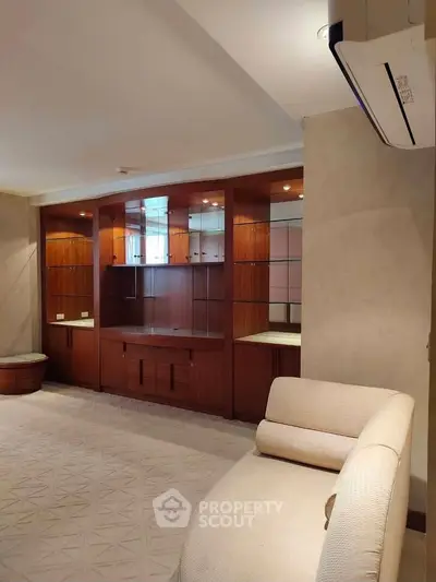 Spacious living room with elegant built-in wooden cabinets and modern air conditioning unit.