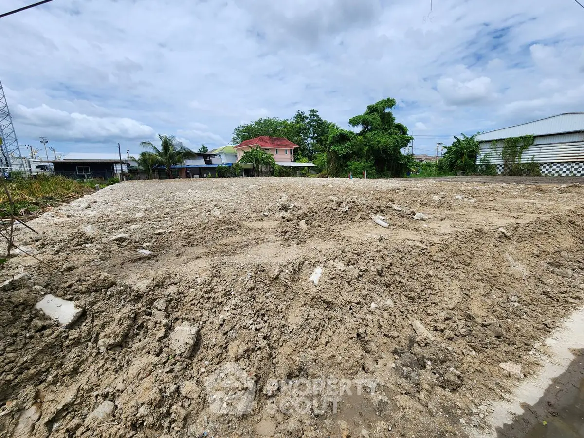 Vacant land plot ready for development with clear skies and surrounding greenery.