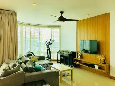 Spacious living room with modern decor and city view, featuring a cozy sofa and entertainment setup.