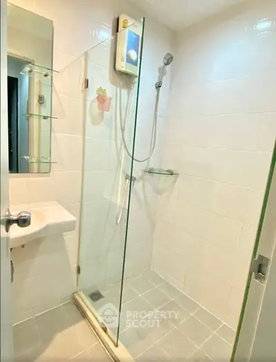 Modern bathroom with glass shower enclosure and sleek fixtures in a contemporary apartment.