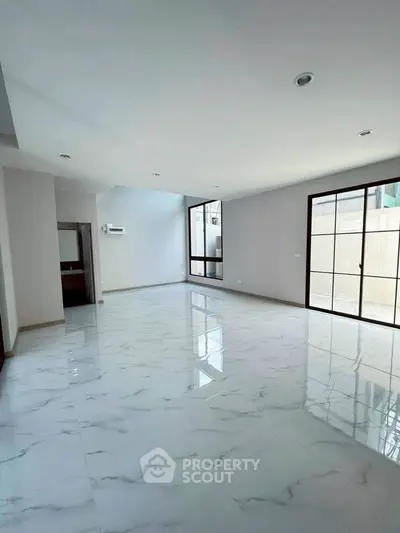 Spacious modern living room with marble flooring and large windows for natural light.