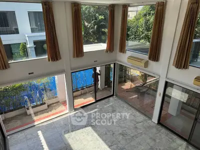 Spacious living room with large windows and garden view, perfect for natural light lovers.